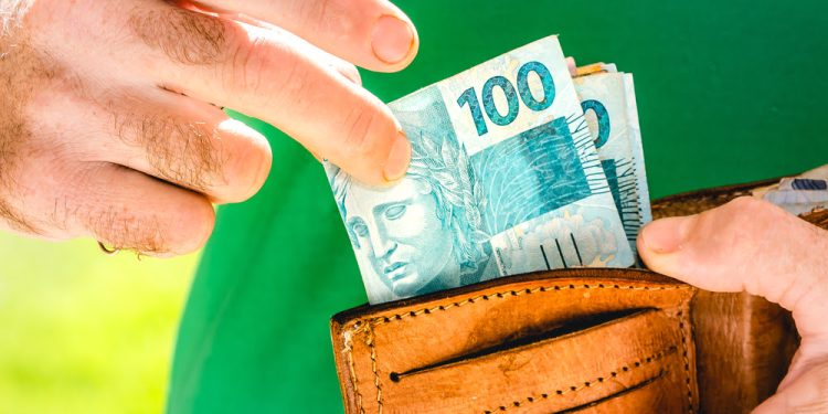 Real Currency. Money, Dinheiro, Brasil, Reais. Man holding in hand a group of Real banknotes. Salary, Laborer, Worker.